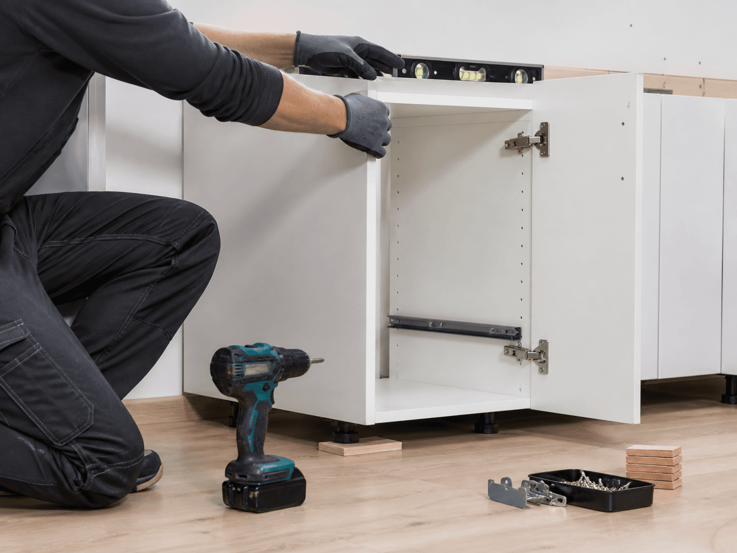 Professional installer leveling a full-access base cabinet